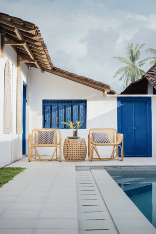 A poolside scene with prominent blues, a rattan poolside set of side table and two chairs. Photo by Hutomo Abrianto on Unsplash