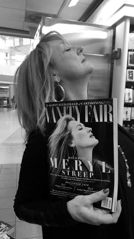 A picture of Robin holding up a magazine cover of Meryl Streep and posing like her.