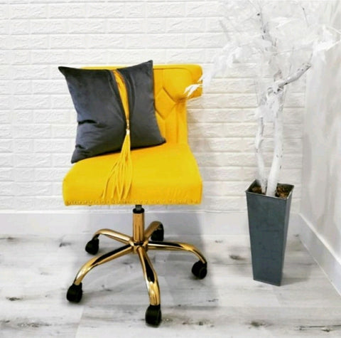 A bright yellow chair with no arms and a whelled base stands against a white brick background. On the chair is a matching UnZipped Pillow