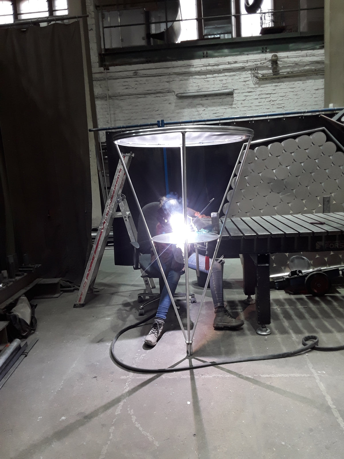 Welding on the “Satellite Warning” sculpture in metal workshop