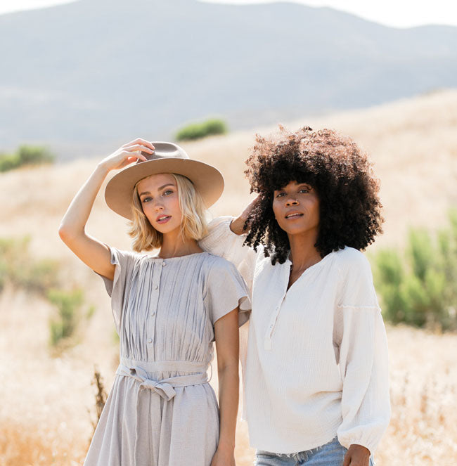 two female friends in trendy clothes looking cool standing in front of golden Californian hills