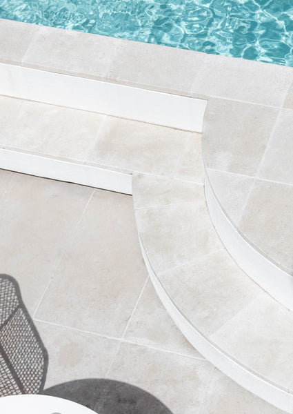 medium shot of light beige marble pavers around a swimming pool