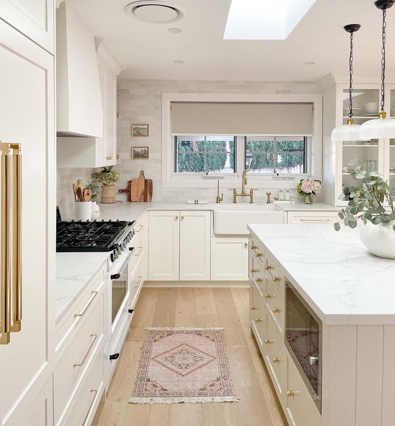 Kitchen with white countertop and cupboards and timber flooring.