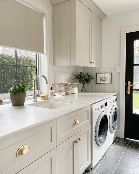 a laundry renovation with grey tiles for flooring and white cabinets.