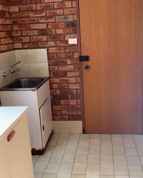 a laundry before renovation with red brick tiles. 