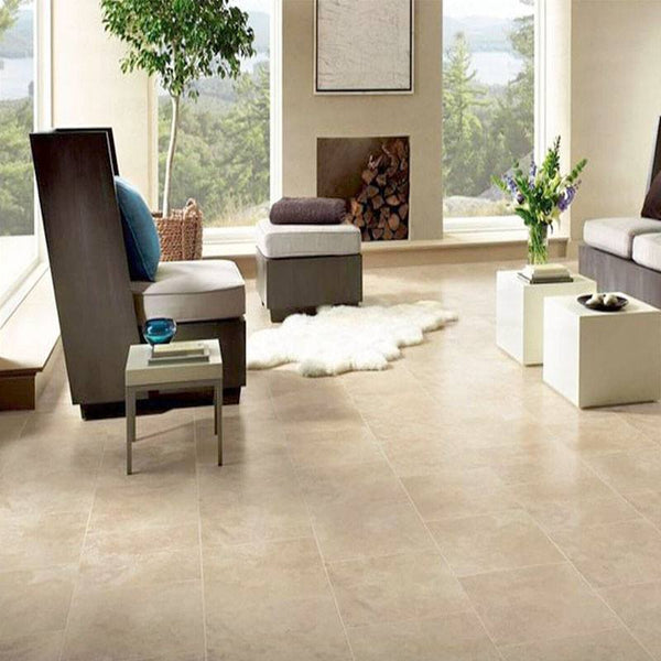 A living room with a fireplace looking out into a forest. The flooring is beige colour natural stone tiles.