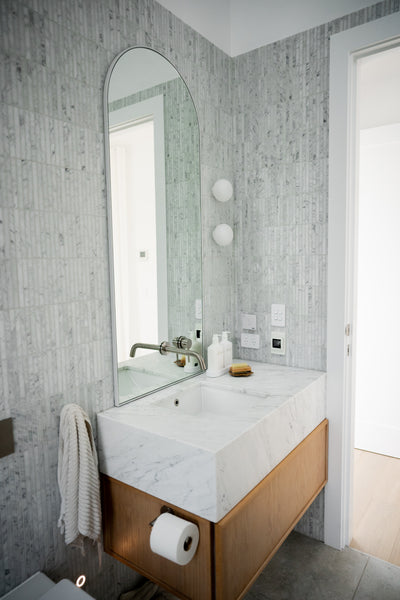 a bathroom sink area with white and grey marble mosaics