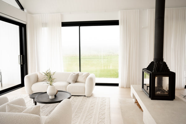 A living room with white sofas and black windows