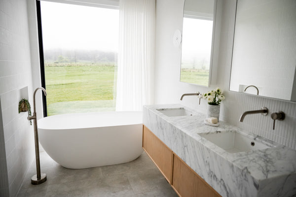 bathroom with floor-to-ceiling window with black framing. There is a white bathtub next to the window.