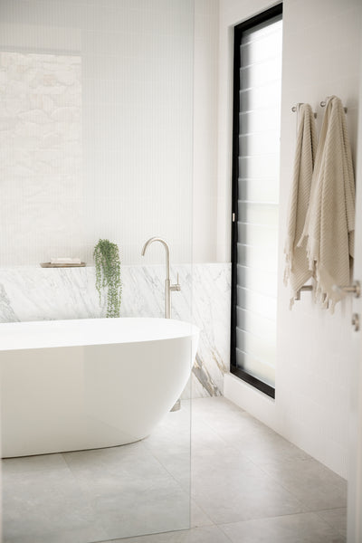 a bathroom with bathtub. There is white and grey marble tiles used in the design.