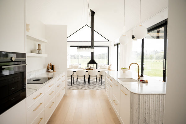 A kitchen with timber flooring and white marble used on the countertop and splashback.