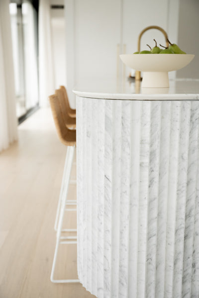 close-up image of white marble concave tiles on a kitchen countertop.