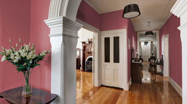 A hallway with timber flooring and the walls are painted with Terra Rosa purple colour.