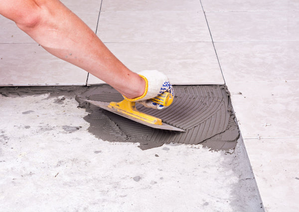 Tiler applying mortar to riles on the floor