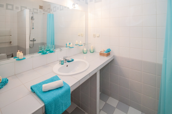 bathroom with white wall tiles and blue features. The bathroom looks extra clean.