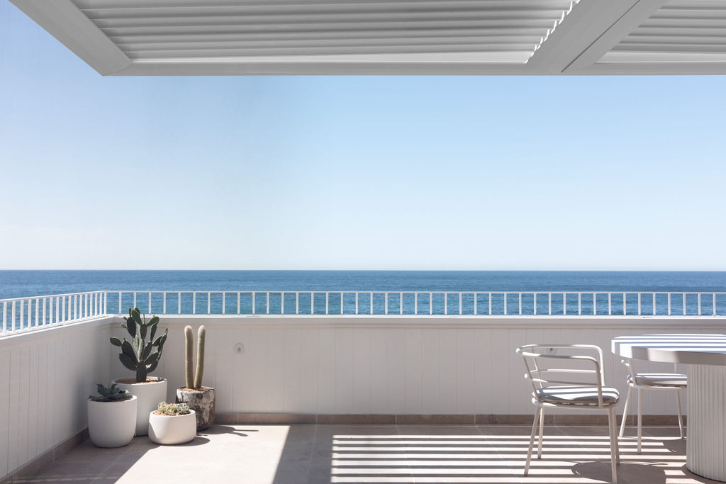 outdoor marble floored balcony with a view of the ocean with two plants as decor