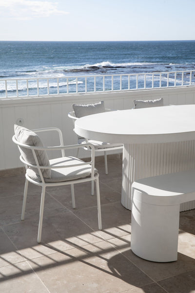 Balcony overlooking the ocean with a table and few chairs on marble flooring