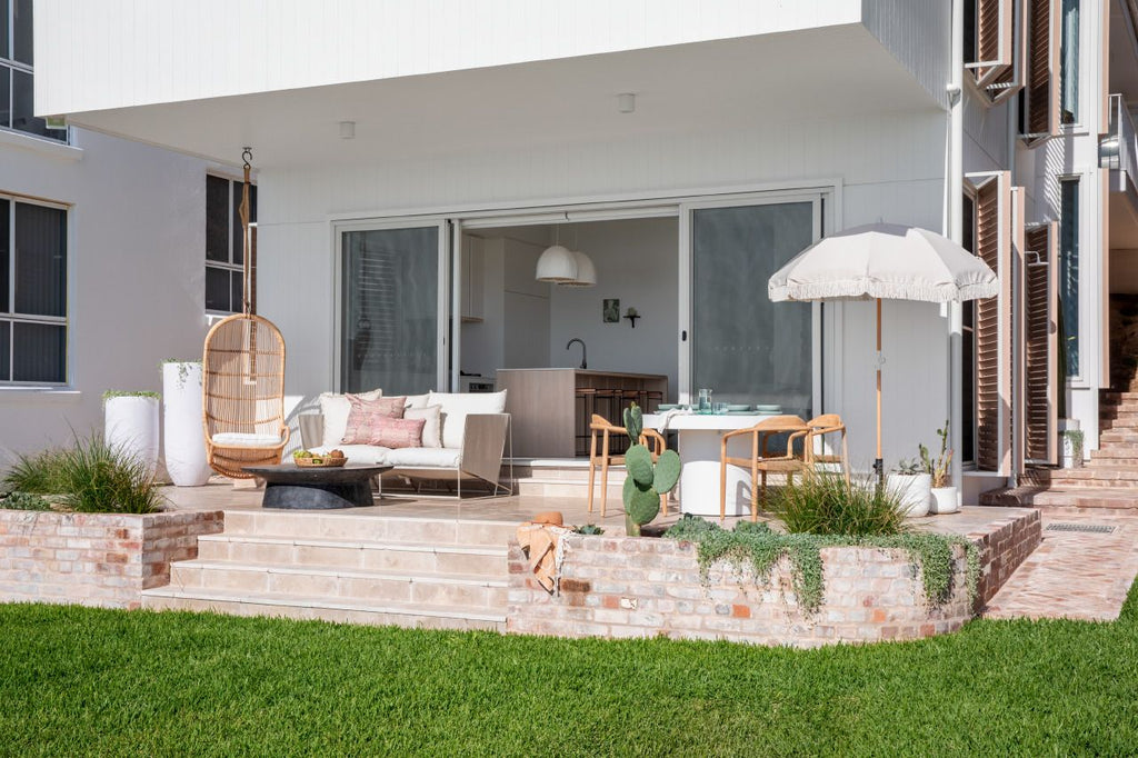 beach home outdoor with light pink marble tiles on the floor and a couch and few chairs