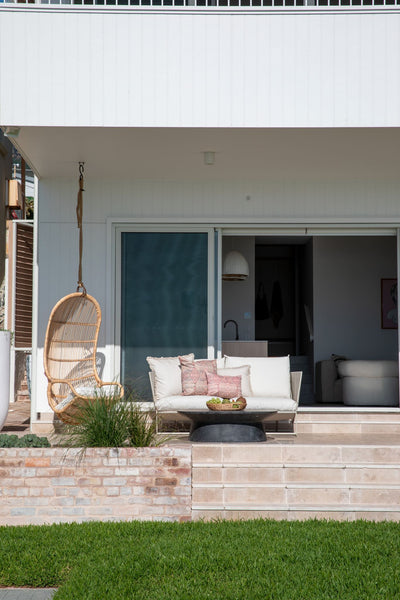 beach home outdoor with light pink marble tiles on the floor and a couch and few chairs