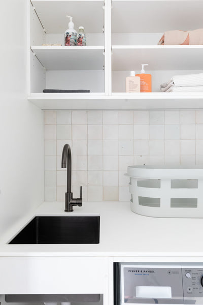 laundry with white ceramic wall tiles and black tapware