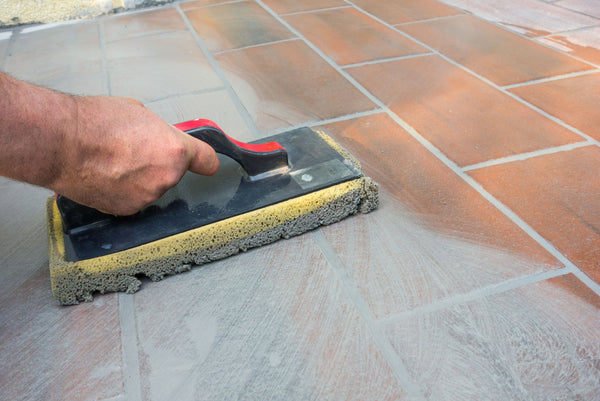 Tiler applying grout to tiles on the floor