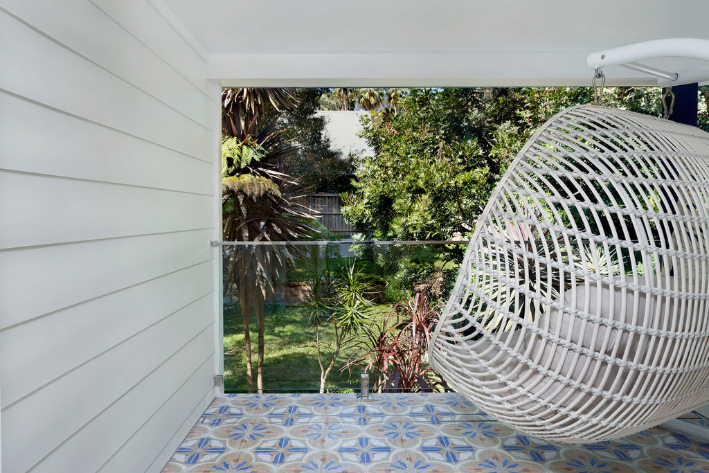 balcony looking into garden with a white chair and Moroccan pattern tiles flooring