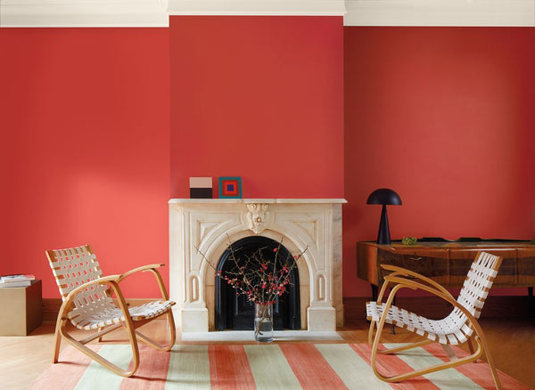 A living room designed with Raspberry Blush red colour. There are two chairs and a fireplace in the room.