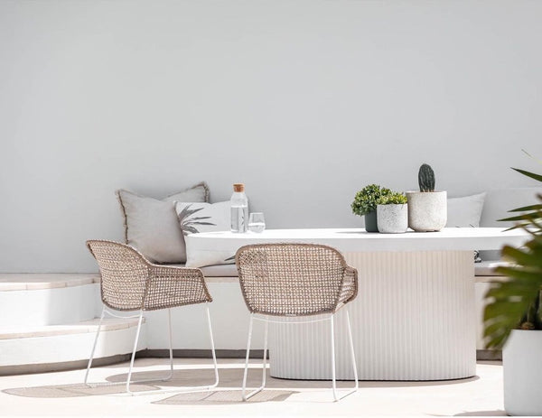 outdoor area with a table and a few white chairs. The floor paver is light beige marble.