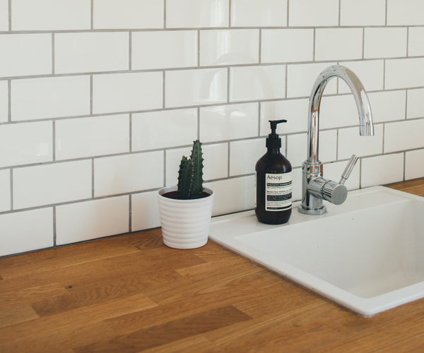 white wall tiles behind a sink laid in brick pattern with dark grouting.