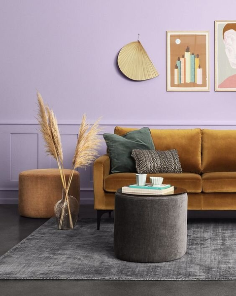 a living room with wall painted in fresh lilac pink and a brown sofa and grey table