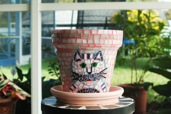 A glass mosaic vase with a cat face design