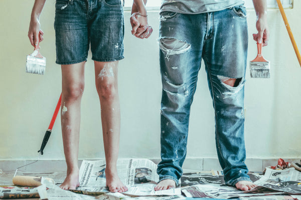 a couple's legs as they are holding painting tools