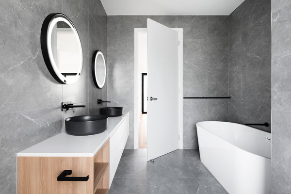 a modern bathroom design with large grey porcelain tiles on the floor and walls. The bathroom features are white and black.