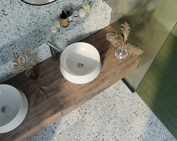 a bathroom sink area with terrazzo tiles and green tiles.