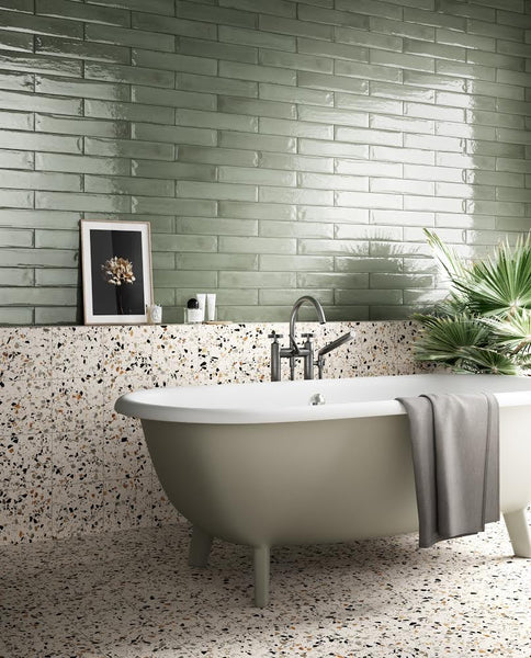 A bathroom with a bathtub. Pink terrazzo-look porcelain tiles and green porcelain tiles are installed on the walls.