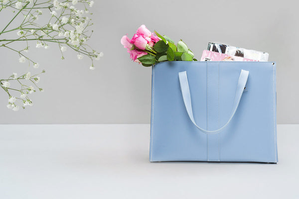 handmade leather shopper in pastel blue with flowers and magazines placed inside
