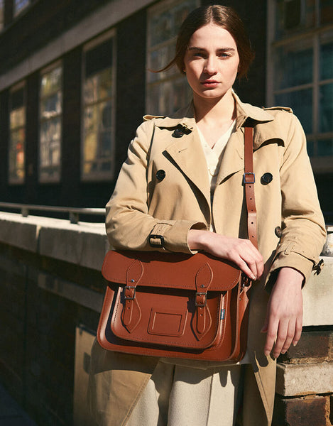 Woman wearing Zatchels classic satchel in chestnut, paired with beige trench coat