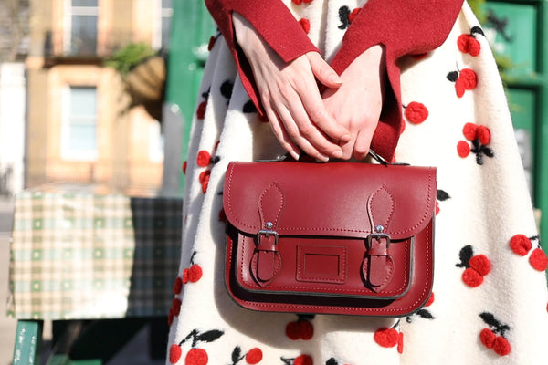 person wearing printed red and white dress holding Zatchels micro satchel in red