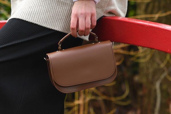person holding Aura handbag in brown