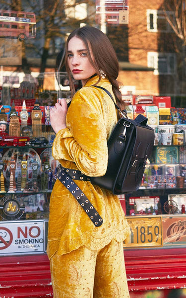 woman wearing yellow co-ord with belt carrying Zatchels city backpack in black