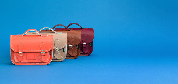 selection of handmade leather satchels in different colours on a blue background