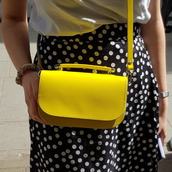 Woman wearing Zatchels Aura bag in daffodil yellow wearing a dotted skirt