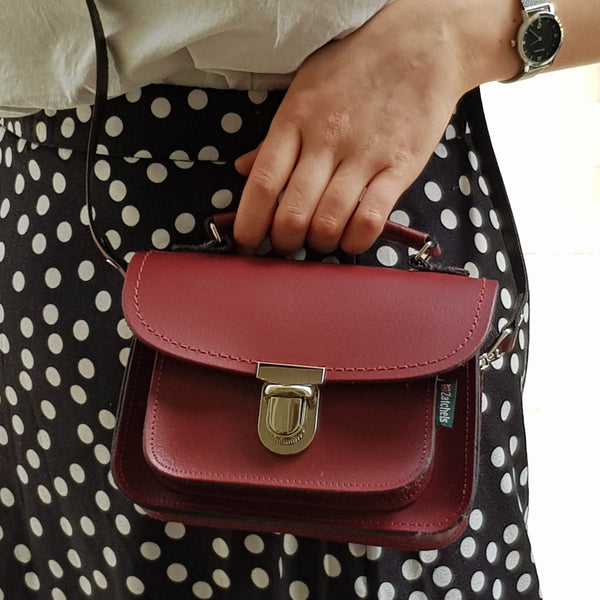 close up of person wearing polka dot skirt holding luna handbag in red