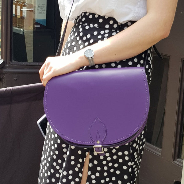 close up of person in spotted skirt wearing purple saddle bag