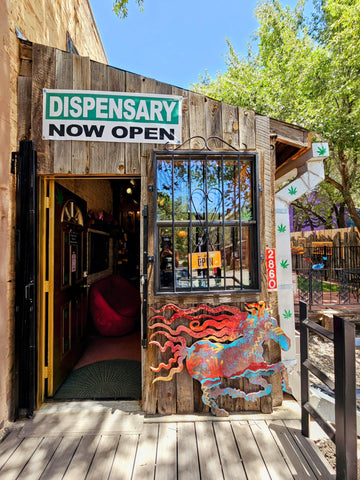 a storefront photo of the tru luv bud dispensary & boutique with an open door and a sign above that reads Dispensary Now Open