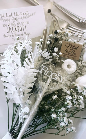 Clear heart lollipop on dried flowers with the name 'Roch in silver icing'