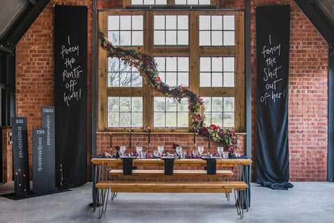 Modern Gothic Romance Wedding Tablescape with Black Wal Hangings against exposed brick walls and picture window. 