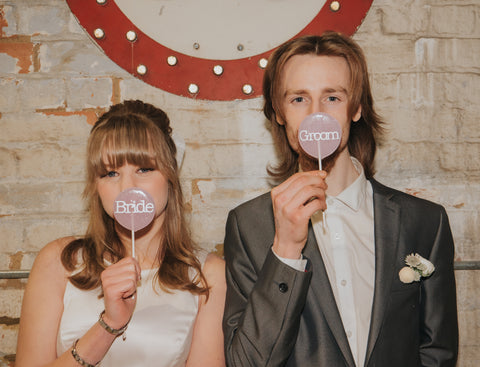Bride and Groom holding pink lollies in front of their mouths