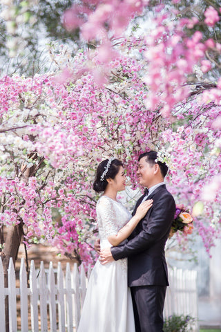 Photo by Esther Huynh Bich from Pexels of bride and groom standing in cherry blossoms