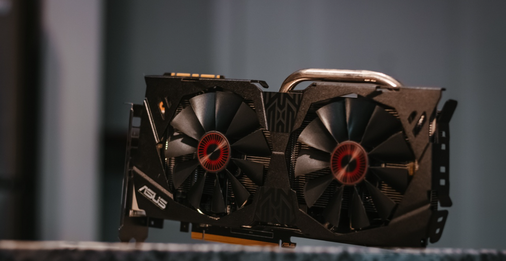 A twin fan ASUS GPU sitting on a worktop. 